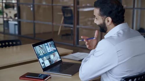 Indian manager leads diverse team videoconference in modern office environment