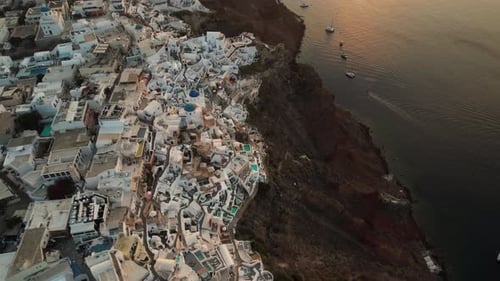 Sunset Above Santorini Island, Oia Village and Aegean Sea, Greece. Aerial View, Revealing Drone Shot