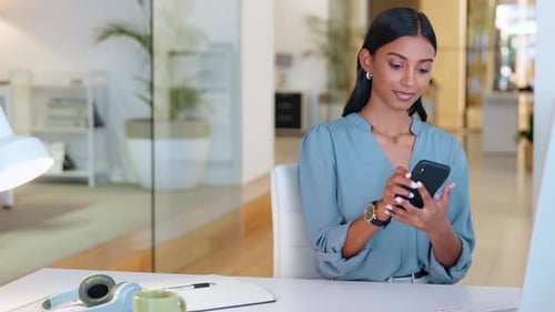 Businesswoman talking on a phone while working on a computer in an office