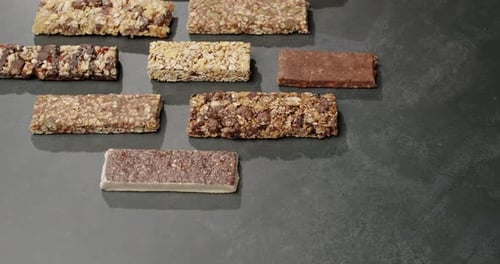 Barritas energéticas variadas sobre superficies oscuras: opciones de refrigerios saludables