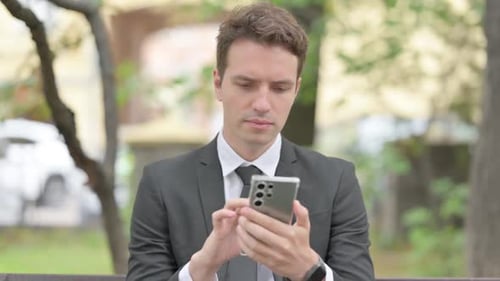 Successful Young Man Celebrating With Smartphone Outdoors