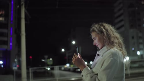 Young Woman Taking Photo on Smartphone By Road Under Night Street Lights