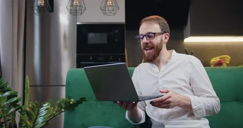 Bearded Man Video Chats on Laptop at Home