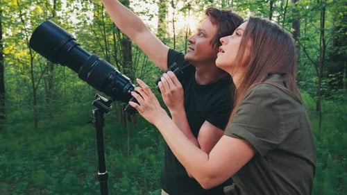 Observation des
oiseaux dans le parc. Couple observe les oiseaux avec des jumelles et un appareil photo avec téléobjectif. Oiseau amateur