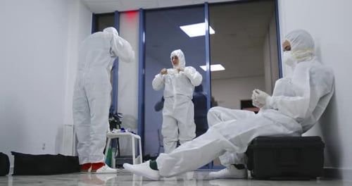 Exhausted Hospital Staff in Hazmat PPE Suits Resting Covid19 Coronavirus Concept