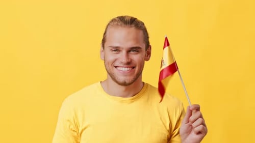 Man Smiles Waving a Flag on Yellow Background
