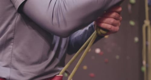 Close-up of Mature Adult Preparing Rope for Rock Climbing at Climbing wall