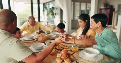 Family Holding Hands at Table for Meal