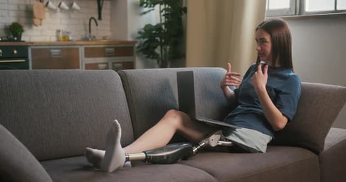 Woman with Prosthetic Leg Using Laptop at Home