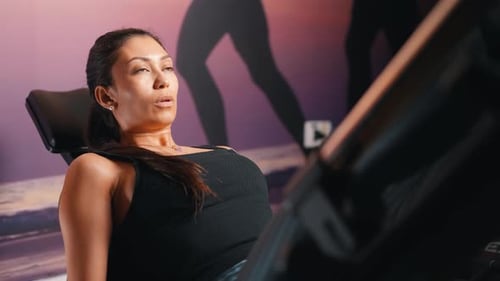 Young woman training legs muscles on leg press machine at the gym side camera movement