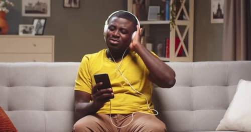 Man Listening to Music on Couch with Headphones