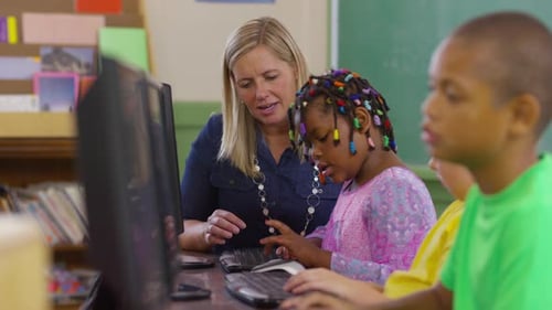 Teacher And Student Working On Computers In School Classroom