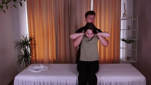 Chiropractor Session in the Massage Studio Woman Sitting on a Couch and the Doctor Holding Her