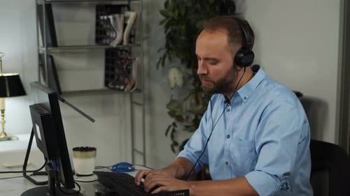Male office worker wearing headphones listens to music