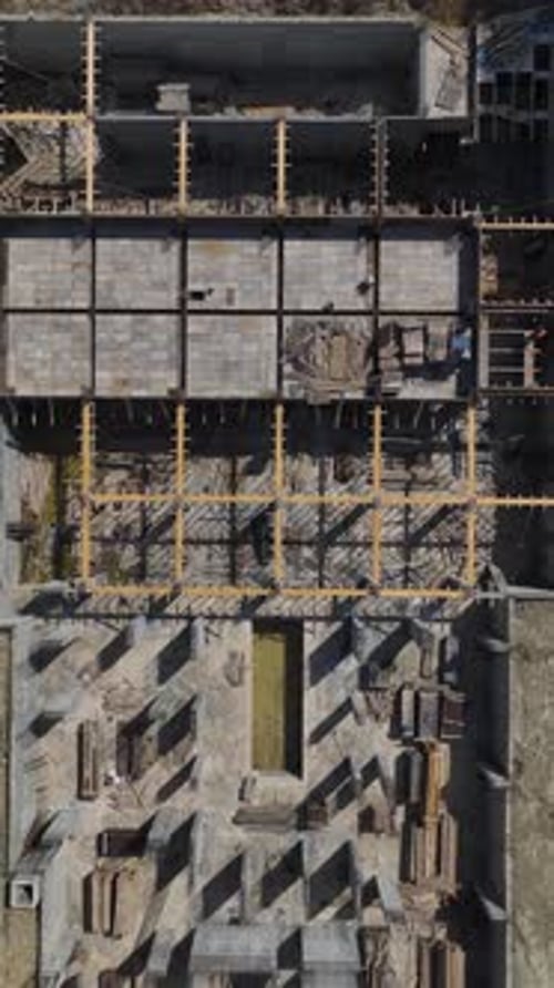 Los ingenieros de vídeo vertical gestionan a los trabajadores que construyen paredes para un nuevo piso en una zona de construcción moderna