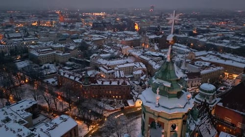 Wawel castle clock tower and Krakow city panorama, night aerial shot in winter