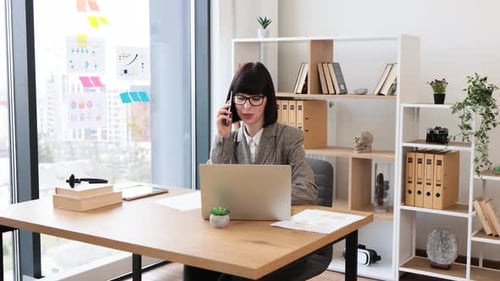 Woman Working at Desk on Laptop and Smartphone