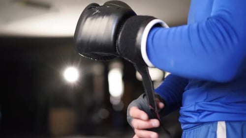 Strong Man Puts on Black Boxing Gloves on Wrapped Fists in Gym Caucasian Sports Man Puts on Boxing