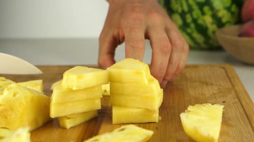 Cutting Pineapple Chunks on Wooden Board