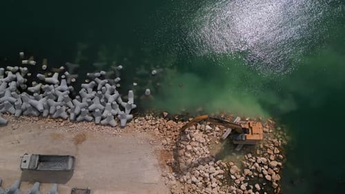 Ein Bagger baut fleißig eine Anlegestelle oder einen Wellenbrecher im Meer, von dem aus sein mächtiger Arm herausragt