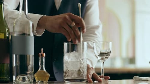 Bartender Stirs Ice in Mixing Glass at Bar