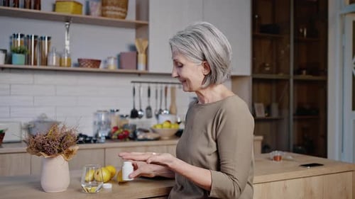 Senior Woman Taking Pills with Glass of Water