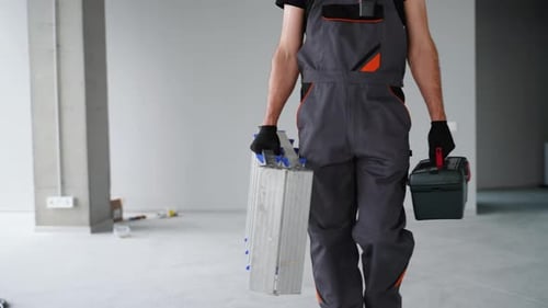 Man Walking with Ladder and Toolbox Indoors