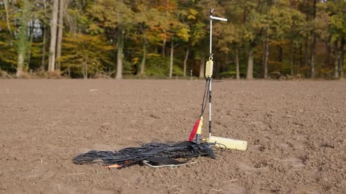 High Resolution Video of a Geophone standing on a field. Next to the Geophone are cables, going into