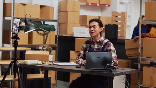 Man Recording Video in Warehouse with Boxes