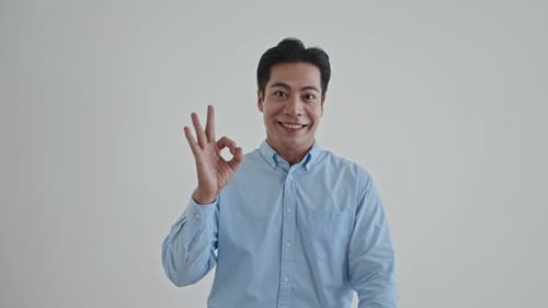 Smiling Man Makes OK Gesture in Mid Shot