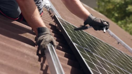 Mounting new installed solar panel on rails, closeup of worker on roof, day