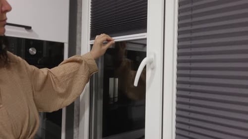 Close Up of Woman Hand Lowering Window Blinds Indoors