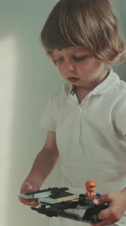 Un niño pequeño construye un diseño de tren vibrante. Un niño pequeño junta cuidadosamente un tren colorido en un lugar cálido