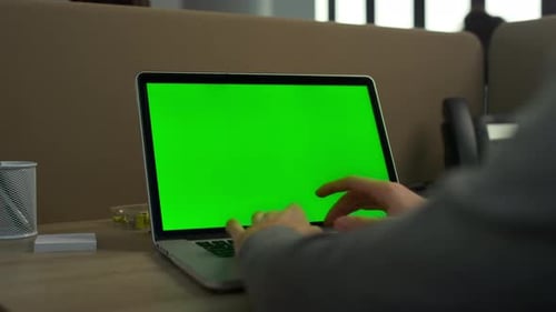 Unrecognizable business man typing laptop computer green screen in modern office