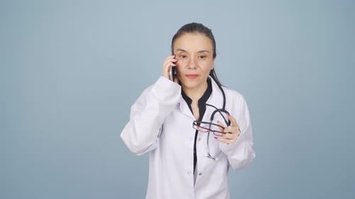 Female Doctor Talking on Phone Holding Eyeglasses