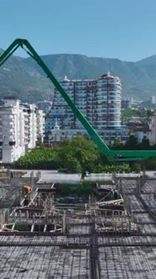 Vídeo vertical: trabajadores vierten hormigón y equipos operativos en una obra de un edificio residencial