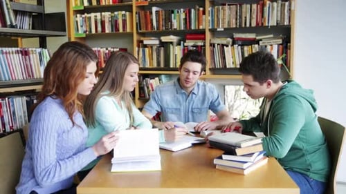 Glückliche Schüler, die zusammen in der Bibliothek lernen