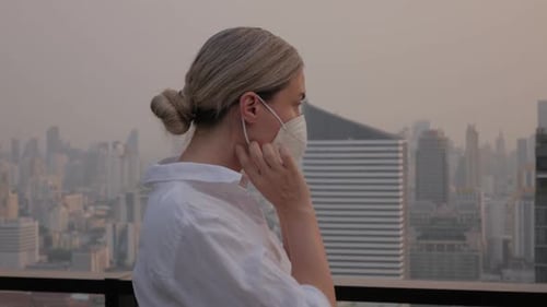 Femme portant un masque de protection debout sur le toit avec les toits de la ville moderne