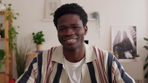 Young Handsome Black Man Smiling at Camera Sitting at Office Workplace