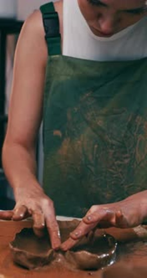 A female ceramicist is creating a new pottery in the workshop.