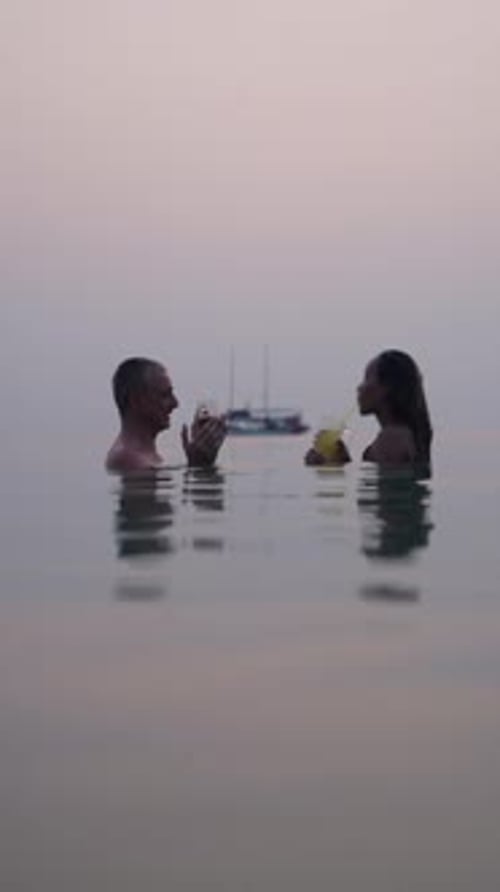 Couple Enjoying Cocktails in Ocean at Sunset