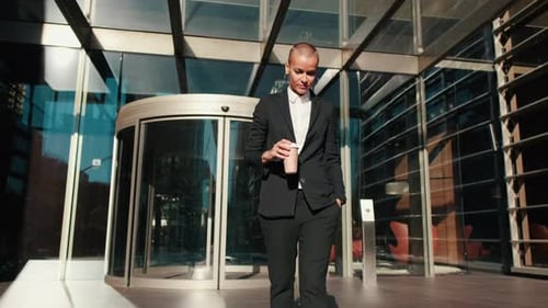 Businesswoman Exits Office Building With Coffee