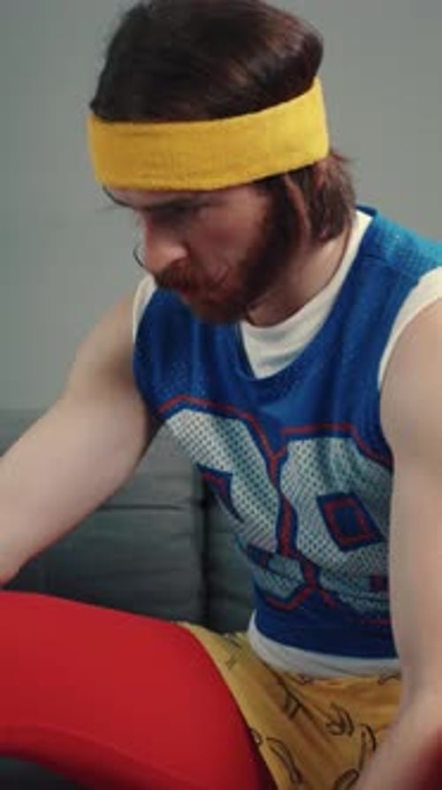 A Man with a Beard and Mustache Works Out Lifting an Orange Dumbbell