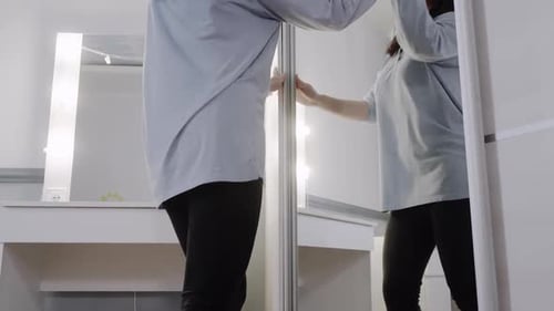 Carefree Woman Dancing While Cleaning Mirror with Cloth in Bedroom