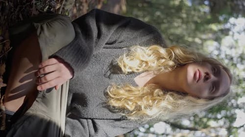 La fille est assise dans les bois entourée de plantes vertes luxuriantes et d'arbres imposants