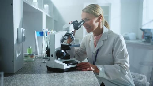 Lächelnde Wissenschaftlerin, die unter die Lupe schaut, Mitarbeiterin im Labor, Medizin, Biotechnologie