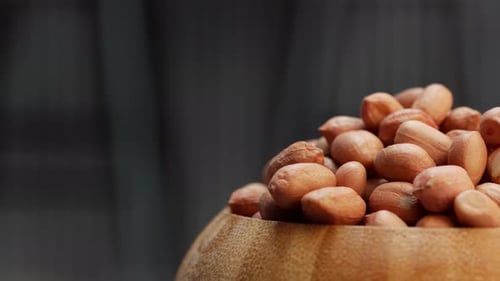 Close up of a bowl of peanuts on a black background