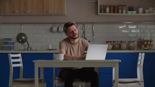 Man Attends Video Call in Blue Kitchen