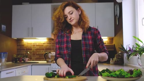 Woman Cutting Cucumbers in Bright Kitchen
