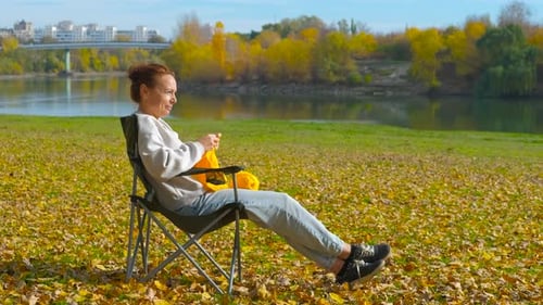 Relaxed Woman Knitting in an Autumnal Park